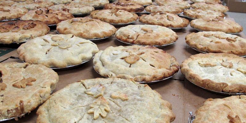 A table top filled with baked apple pies.